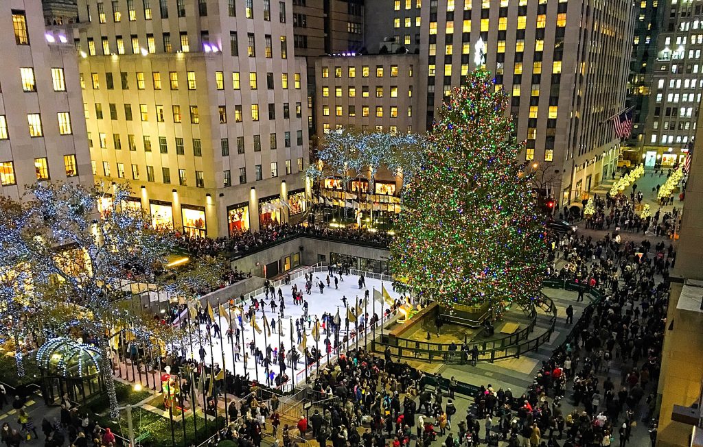 A scenic overview of the hustle and bustle of the holidays at night beneath the magnificent tree in Rockefeller Center to illustrate New York Christmas Incentives | Element